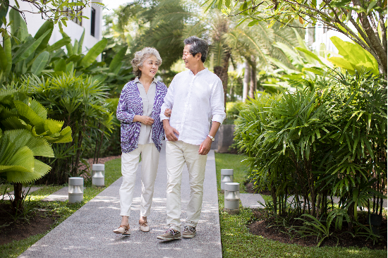 Happy senior Chinese couple walking in courtyard